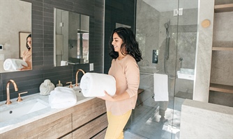 Woman brings freshly cleaned towels into a bathroom